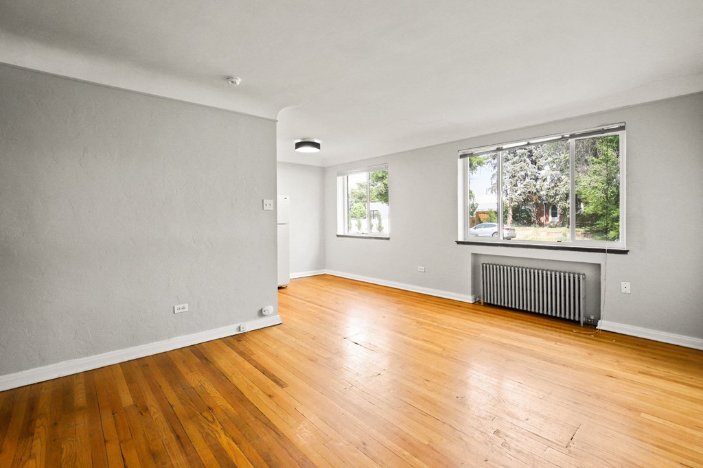 the living room of a house with wood floors and a large window