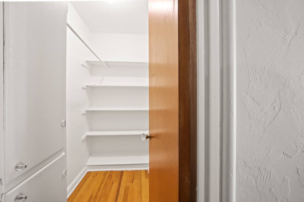 a bedroom with a closet with shelves and a door