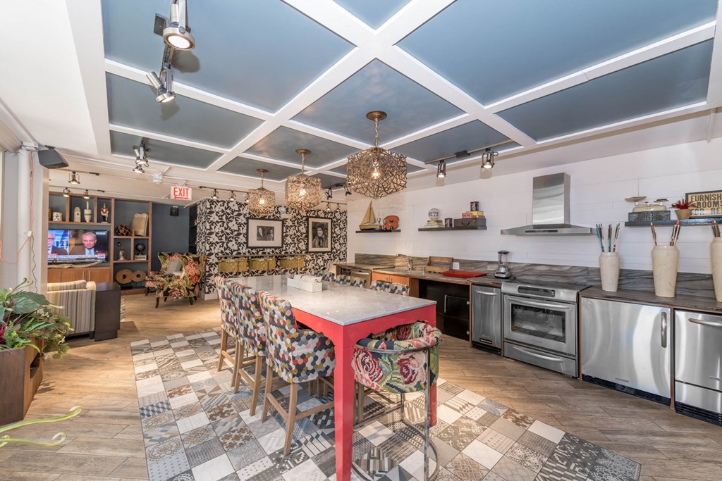 a dining room with a long table and a kitchen with stainless steel appliances