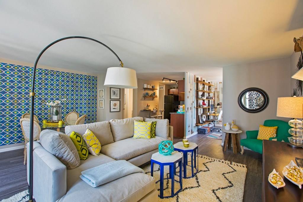 a living room with a white couch and blue and yellow pillows