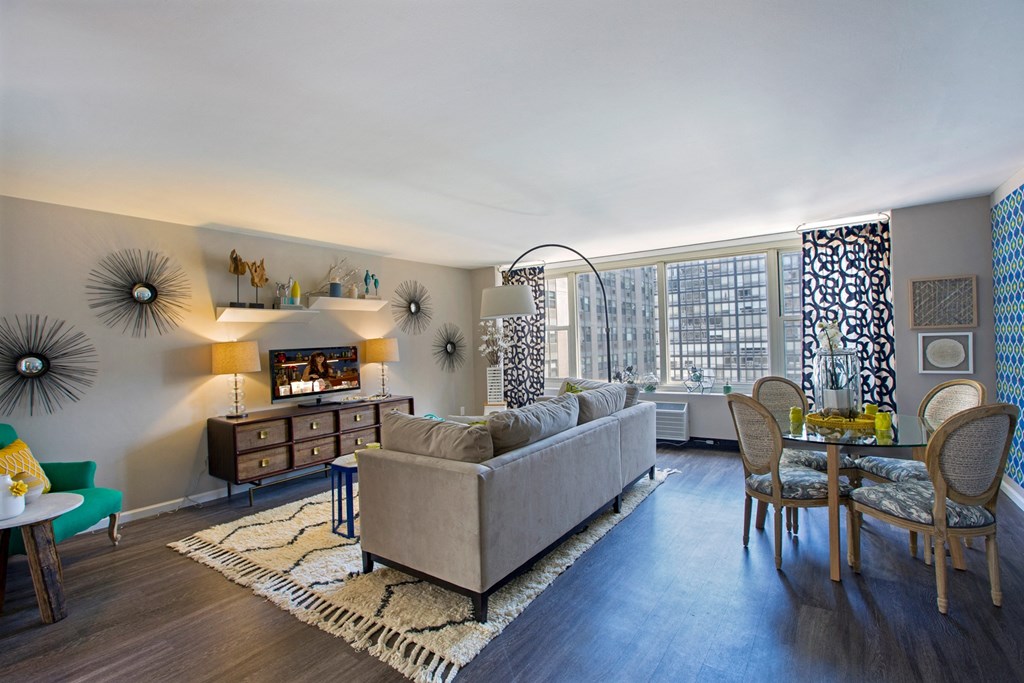 a living room with a couch and a dining room table and a large window