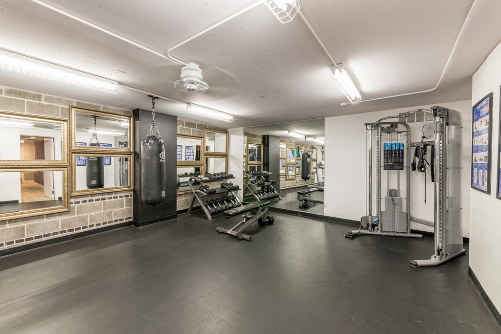 a gym with weights and cardio equipment in the corner of a room