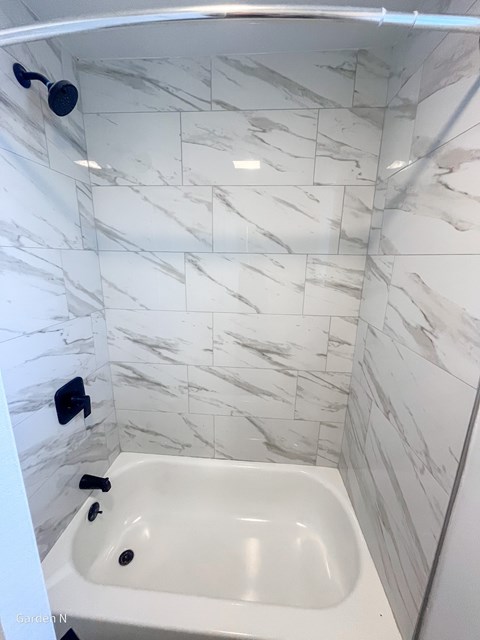 A white marble tiled bathroom with a white bathtub.