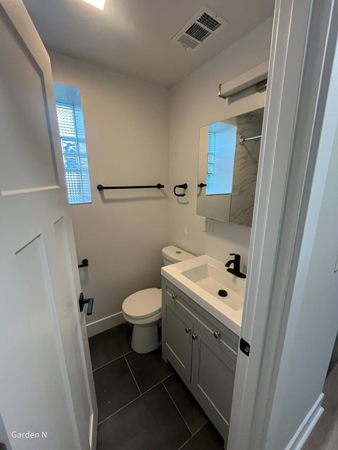 A bathroom with a toilet, sink, and mirror.