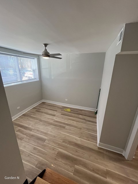 A room with a ceiling fan and a window with blinds.