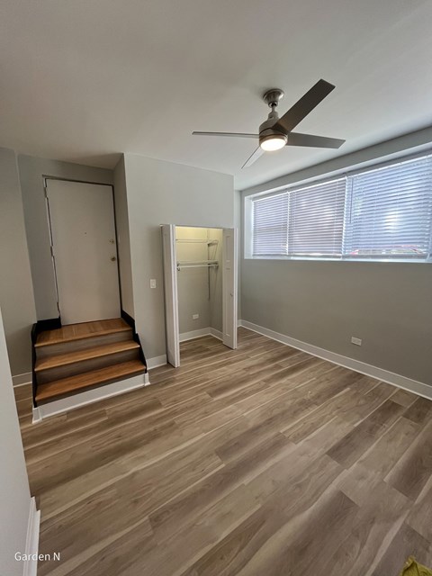 A room with a ceiling fan and wooden flooring.