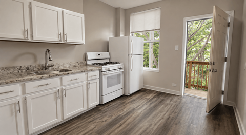 A kitchen with white cabinets and a wooden floor.