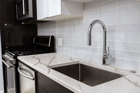 A kitchen with a sink and a black oven.