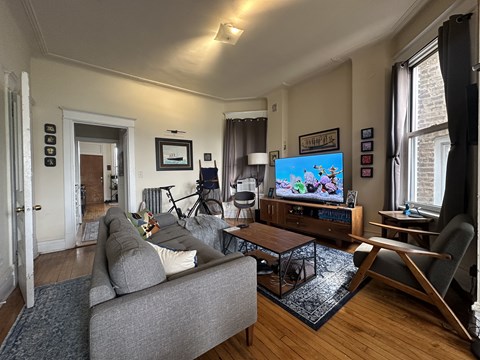 A living room with a grey couch and a television on a wooden cabinet.