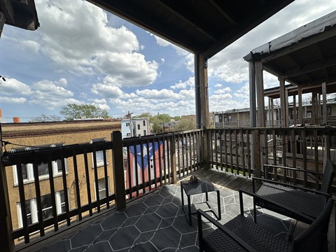 A balcony with a bench and a table with a view of the sky and buildings.