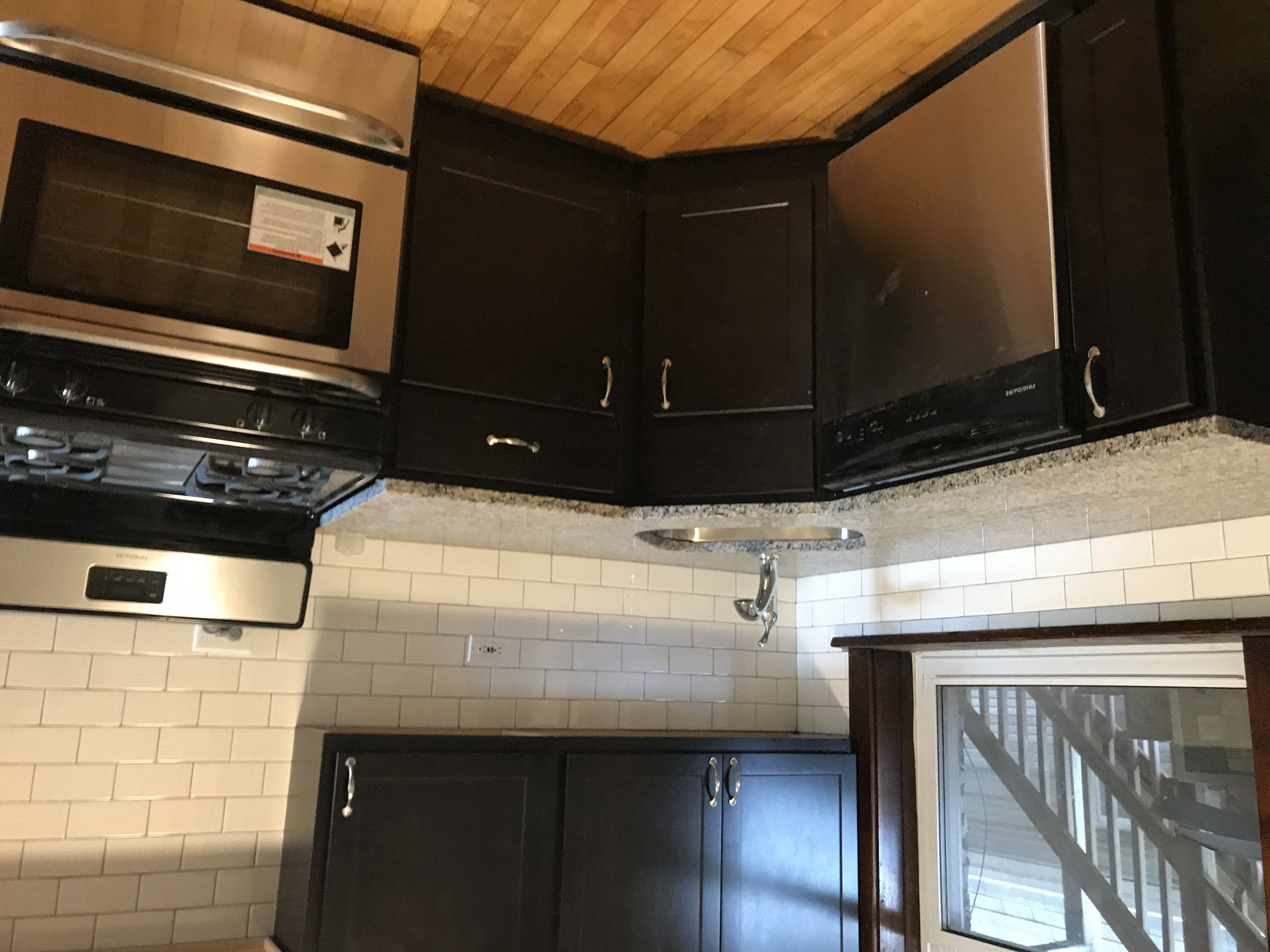 a view of a kitchen with black cabinets and a window