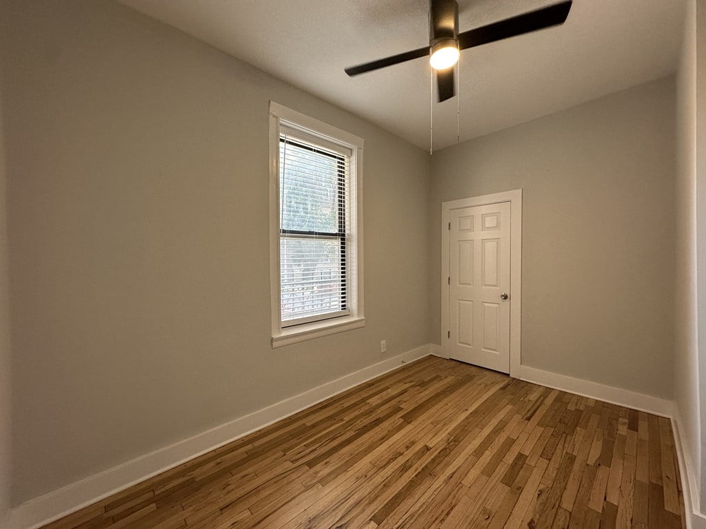 A room with a ceiling fan and a window with blinds.