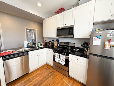 A kitchen with white cabinets and black countertops.