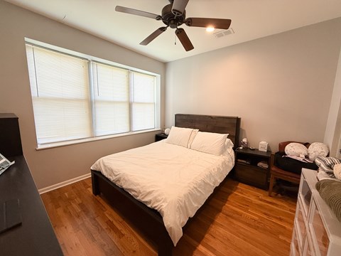 A bedroom with a bed, nightstand, and a ceiling fan.
