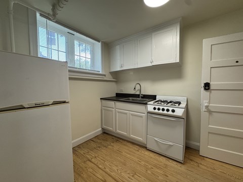 A kitchen with a white stove and cabinets.