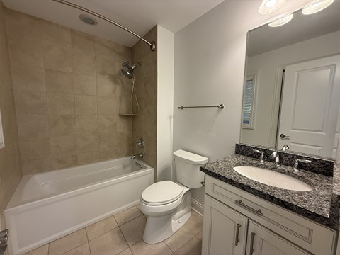 A white toilet sits next to a bathtub in a bathroom.
