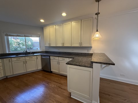 A kitchen with white cabinets and a granite countertop.