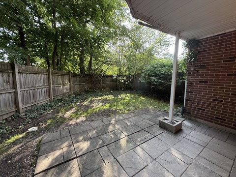 A patio with a white pillar and a brick wall.