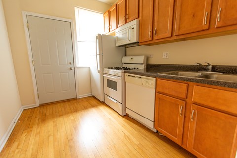 A kitchen with wooden floors and white appliances.