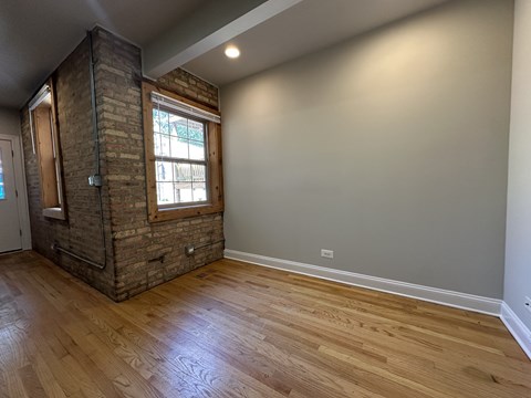 A room with a brick chimney and wooden flooring.