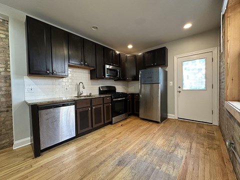 A kitchen with wooden floors and stainless steel appliances.