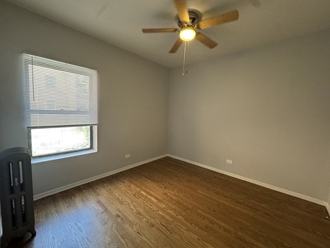 A room with a ceiling fan and a window with blinds.