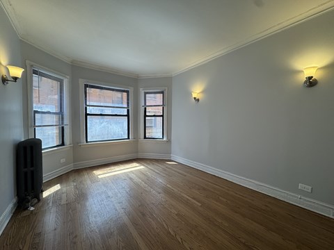 A room with wooden floors and three windows.