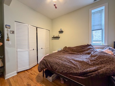 A bedroom with a bed, a window, and a closet.