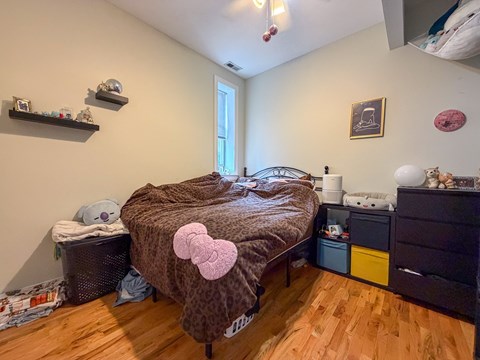 A bedroom with a bed, dresser, and shelves.