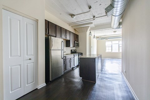 A kitchen with a refrigerator, oven, and cabinets.