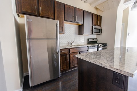 A kitchen with a stainless steel refrigerator and dark wood cabinets.