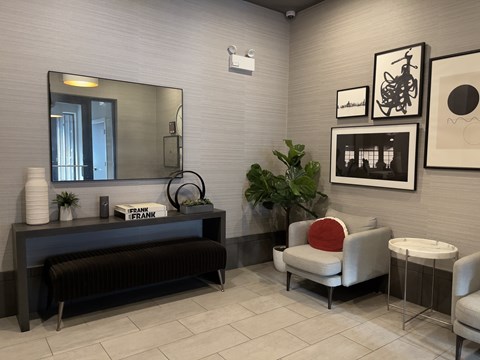 A waiting room with a bench, chair, and potted plants.