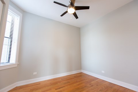A room with a ceiling fan and wooden floors.