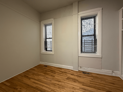 A room with two windows and wooden flooring.