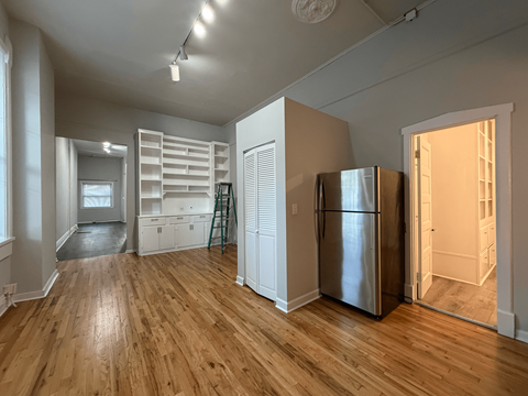 A kitchen with a refrigerator and wooden floors.