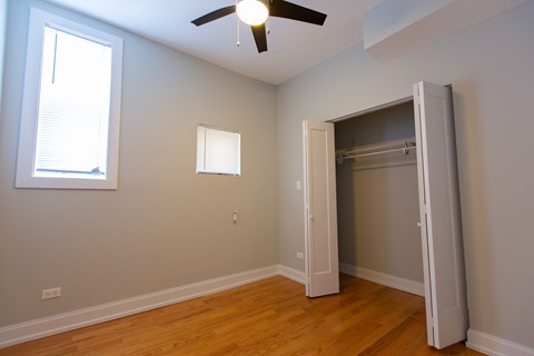 A room with a ceiling fan and a closet.