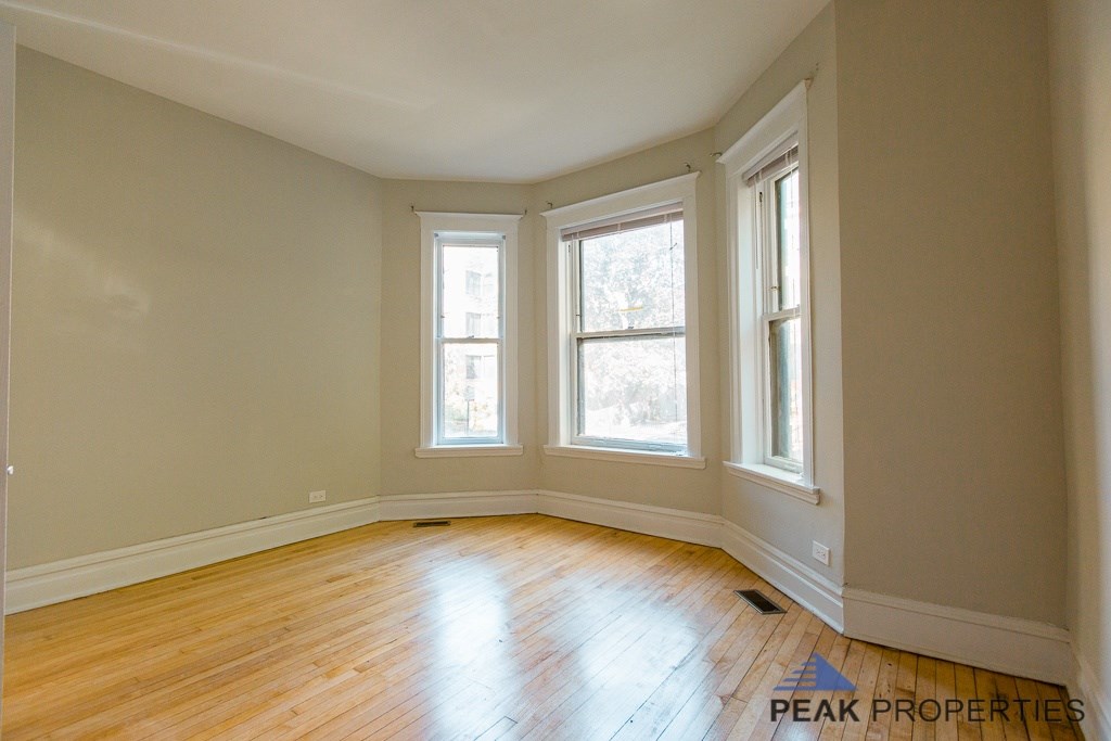 A room with wooden floors and three windows.
