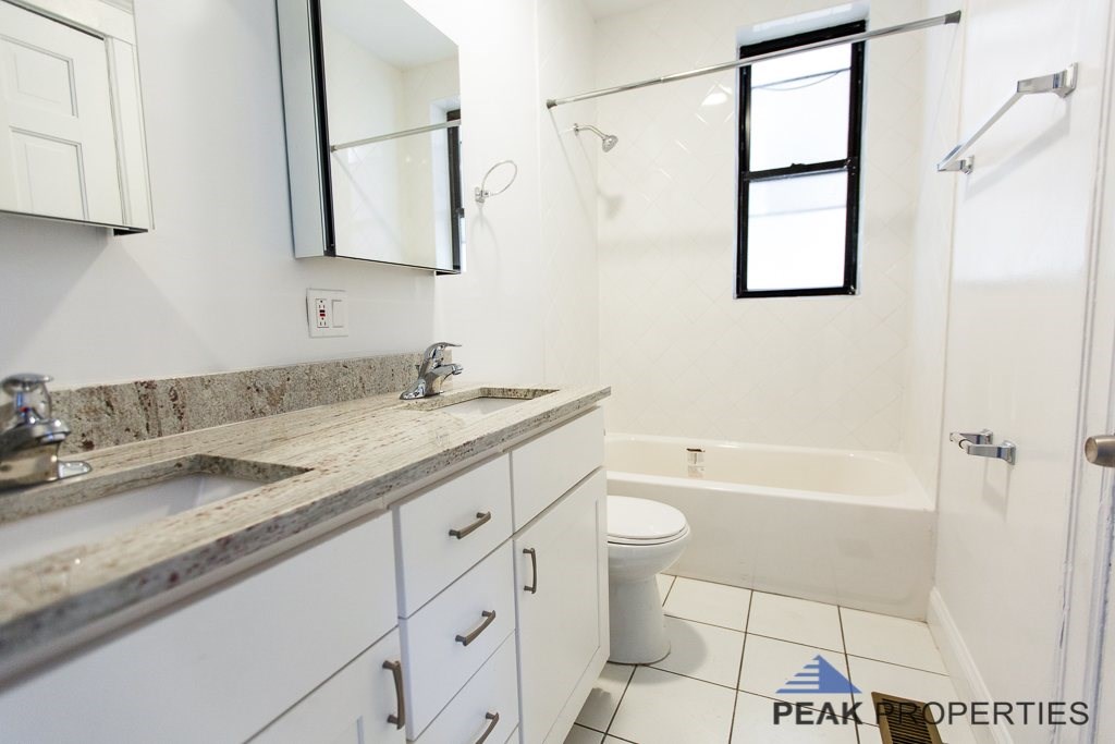 A bathroom with a sink, mirror, toilet, and bathtub.