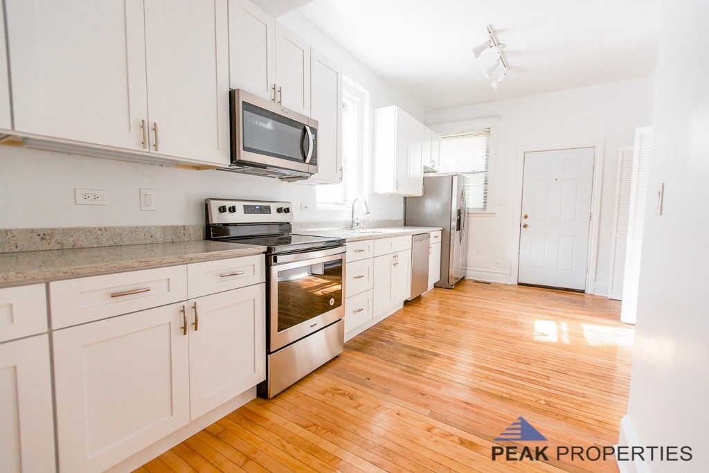 A kitchen with white cabinets and a wooden floor.