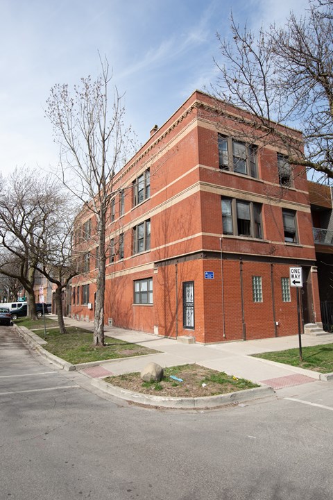 A red brick building with a tree in front of it.