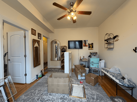 A room with a ceiling fan and boxes on the floor.