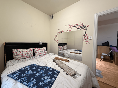 A bedroom with a large bed and a mirror with a cherry blossom design on it.