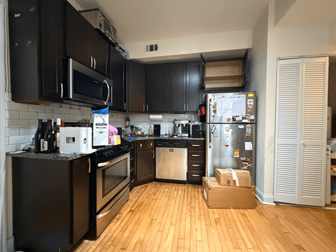 A kitchen with black cabinets and a white fridge.