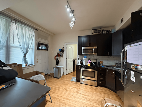 A kitchen with wooden floors and black cabinets.