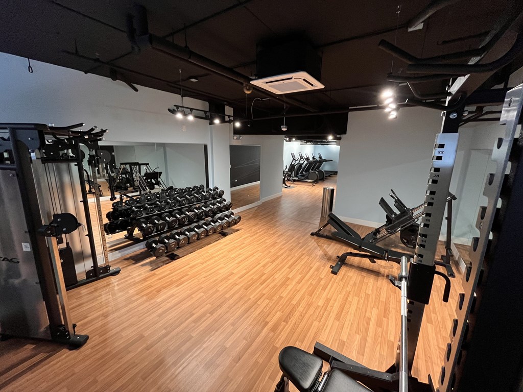 A gym with a variety of equipment including treadmills, weights, and exercise machines.