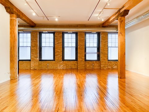A large empty room with wooden floors and brick walls.