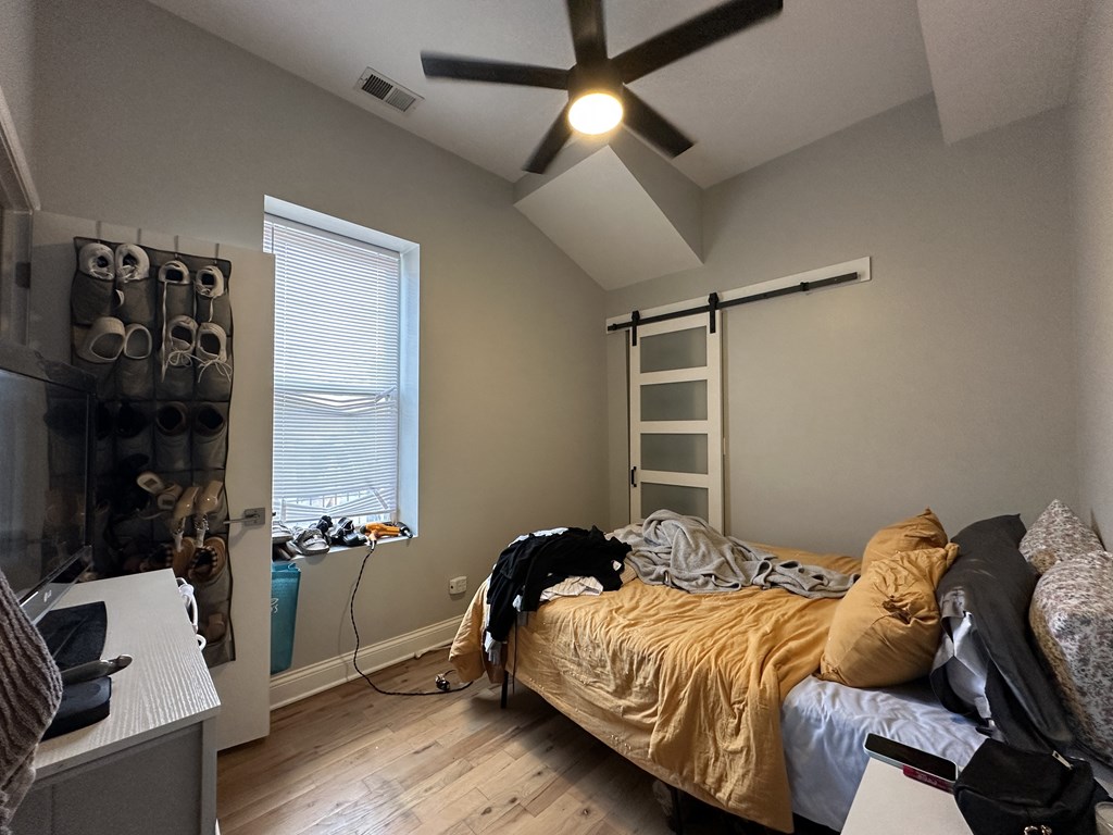 A bedroom with a bed, a window, and a ceiling fan.