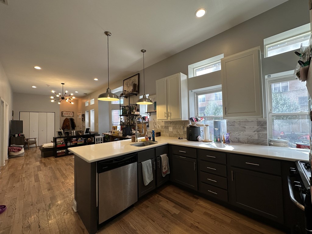 A modern kitchen with dark wood floors and stainless steel appliances.