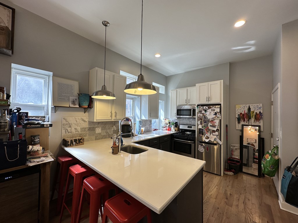 A kitchen with a white countertop and red stools.