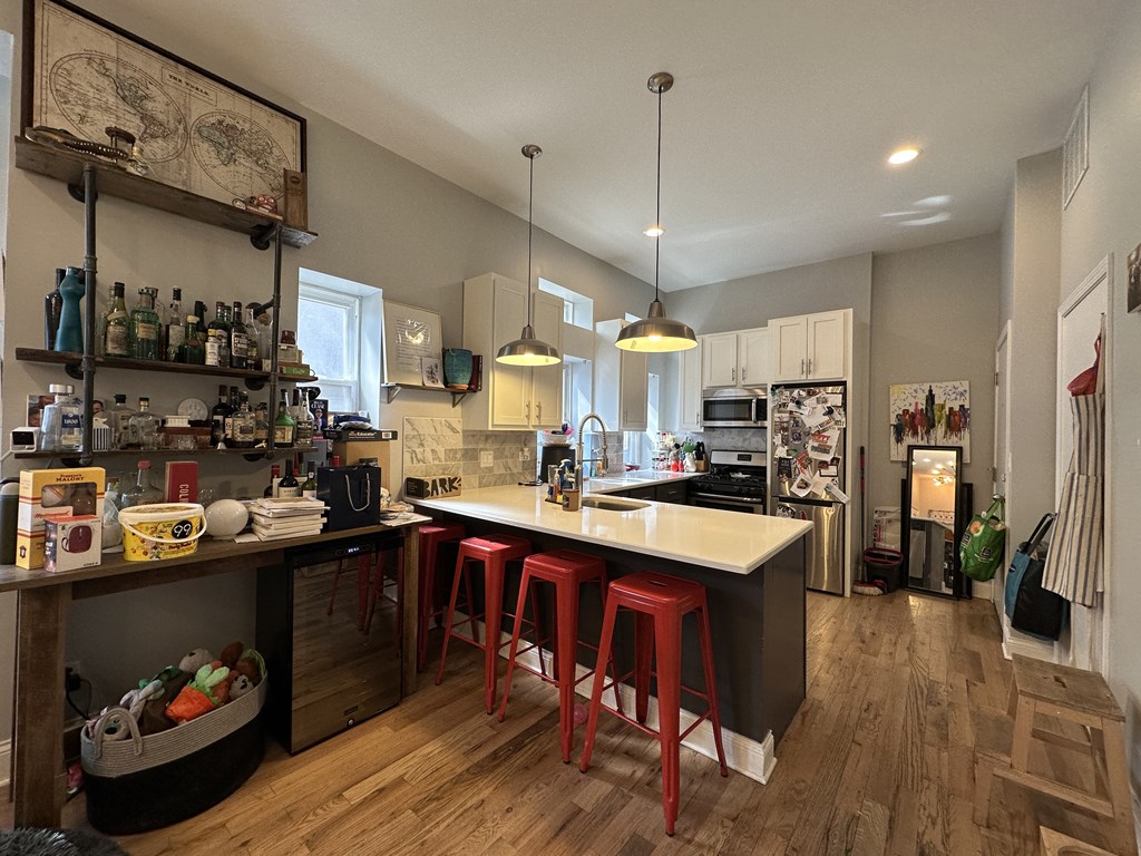 A kitchen with a white countertop and red stools.